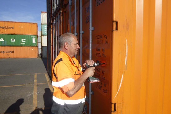Arbeiter montiert Nexxiot-Gerät am Container