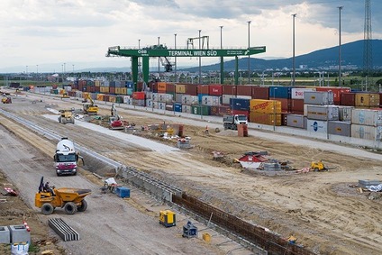 Blick auf das Baufeld mit Baufahrzeugen, im Hintergrund Containerkran mit Containern