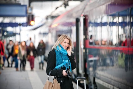 Woman holding her mobile at the station platform.