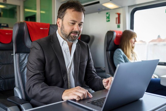 Ein Mann im Zug, der am Computer arbeitet