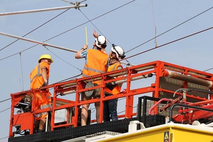Arbeiter stehen auf einem Motorturmwagen und reparieren eine Oberleitung