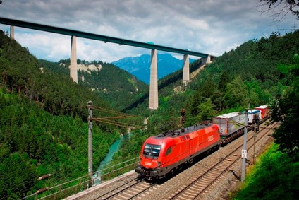 © ÖBB/Hanno Thurnher Fahrender Güterzug, im Hintergrund die Autobahnbrücke Brenner