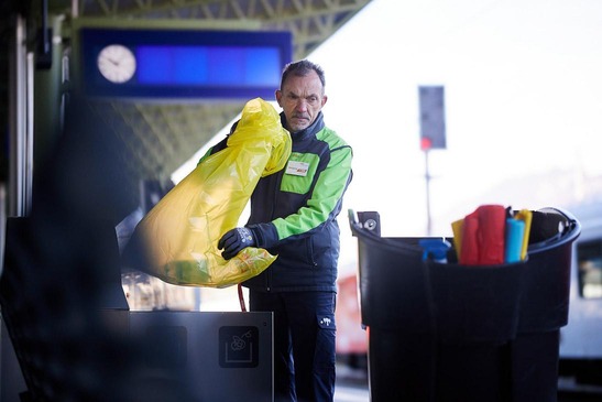 Ein Reinigungsmitarbeiter wechselt einen gelben Müllsack in einer Recyclingstation am Bahnhof Villach.