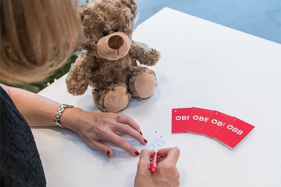 © ÖBB/Wegscheider Frau schreibt auf Papier, daneben ÖBB Karten und der Lost & Found Bär