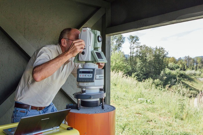 A surveyor measures the surrounding landscape.