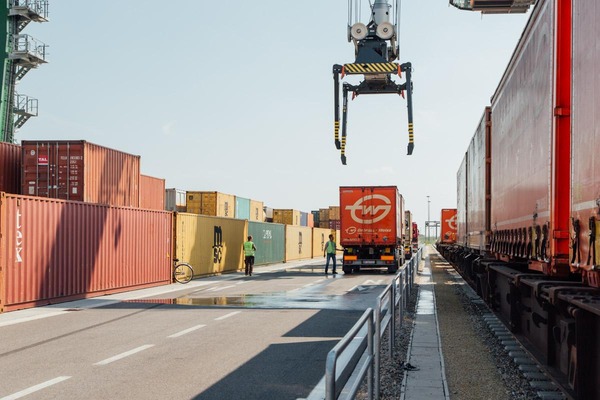 Ein Portalkran verlädt mehrere Container auf ein Lastkraftfahrzeug.