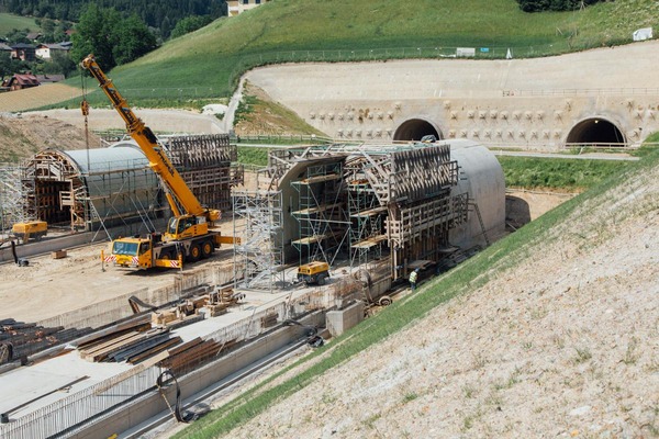 Mehrere Bauarbeiter arbeiten an einer freistehenden Tunnelröhre.