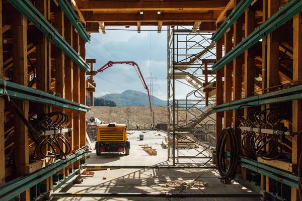Mehrere Bauarbeiter befüllen eine Fläche mit Beton.