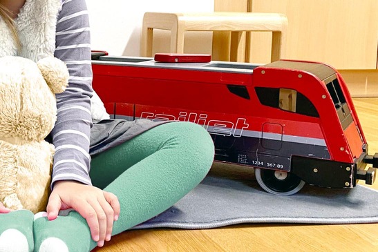 Kind mit Spielzeug Railjet.