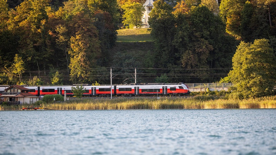 Der neue ÖBB Cityjet Doppelstock unterwegs in idyllischer Landschaft mit See und Bäumen