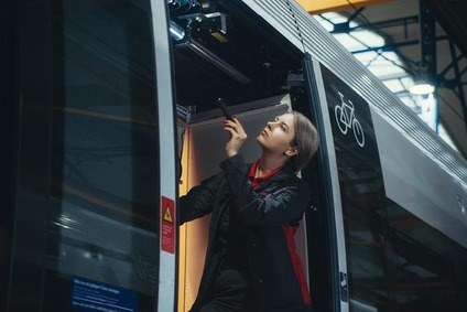 Frau in einem Zug stehend, in grauer Uniform, inspiziert mit einer Taschenlampe den Zug.