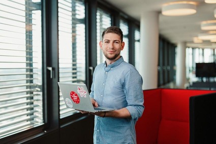 Mann mit blauen Hemd und Laptop in der Hand