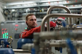 Mann mit Ohrenschutz arbeitet an Rohren.