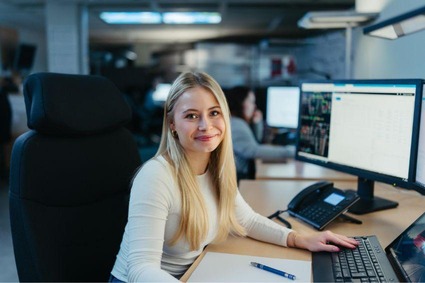 Frau mit langen blonden Haaren am Bildschirm sitzend 