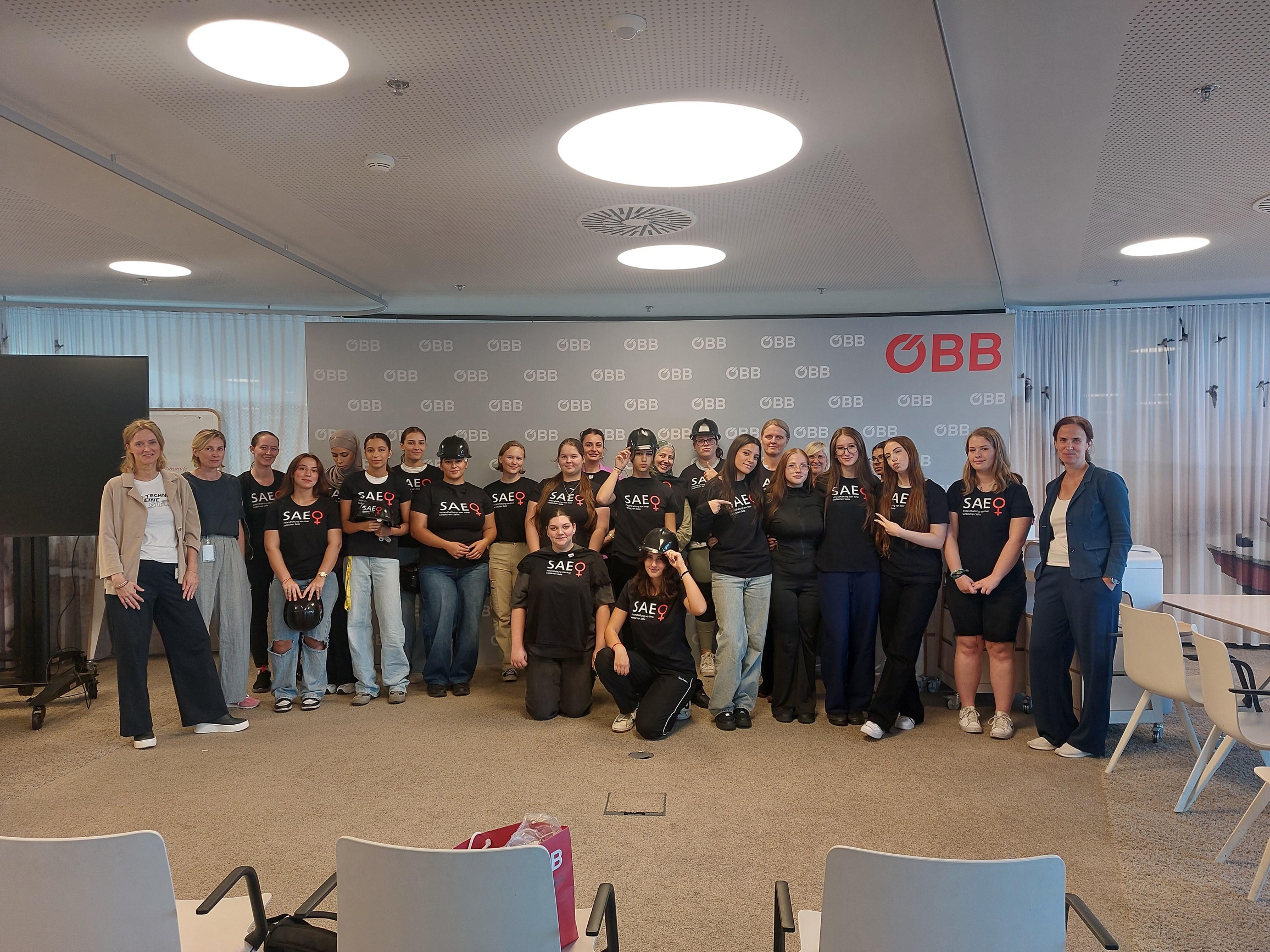 Gruppe von Frauen die vor einer ÖBB Wand stehen.