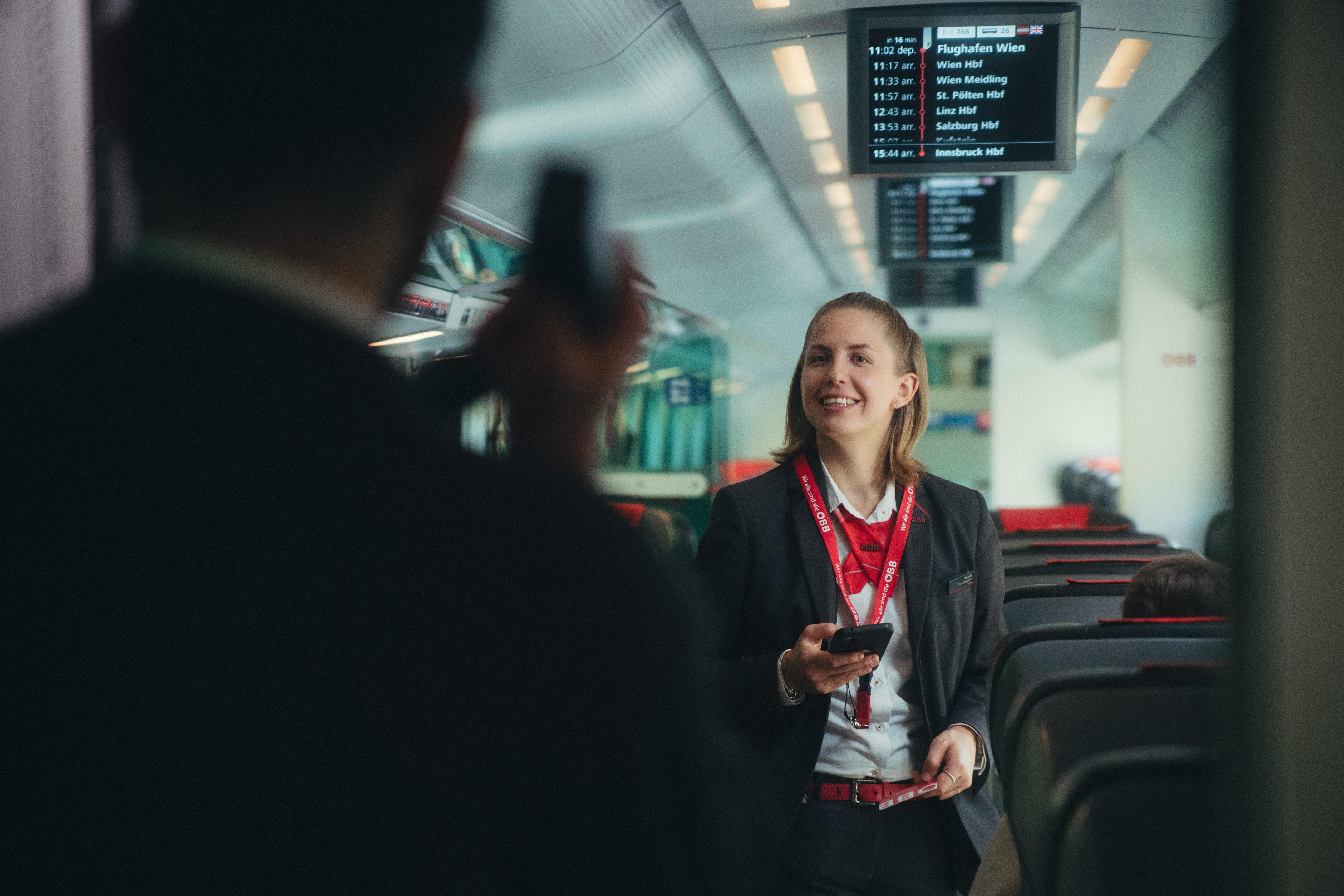 Eine Zugbegleiterin lachend im Zug stehend in Uniform.