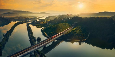Zug über eine Brücken fahrend bei Sonnenuntergang.<br/>