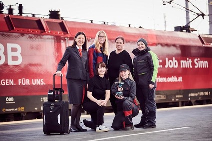 Eine Frauengruppe mit unterschiedlichen Uniformen am Bahnsteig stehend.