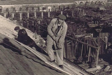 Sowjetischer Zwangsarbeiter bei Dachreparaturarbeiten im Reichsbahnausbesserungswerk Floridsdorf, im Hintergrund die Floridsdorfer Hochbahn