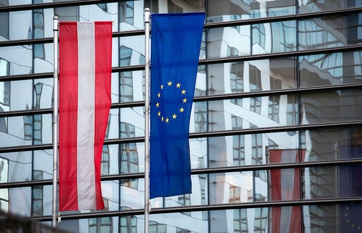 Österreich- und EU-Flagge vor verglastem Gebäude