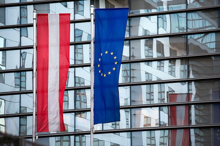 Österreich- und EU-Flagge vor verglastem Gebäude