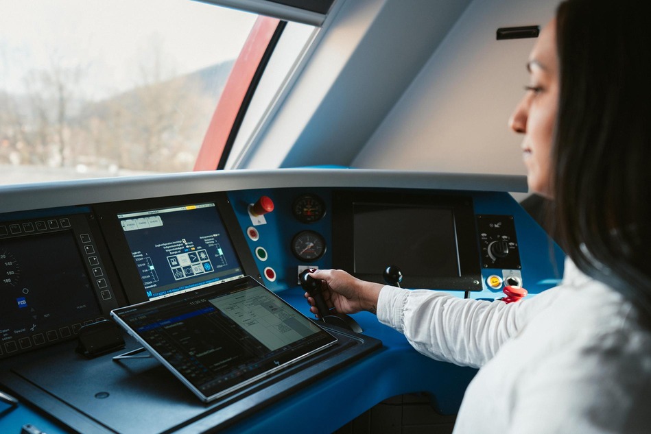 Triebfahrzeugführerin der ÖBB bedient Schaltflächen im Führerstand