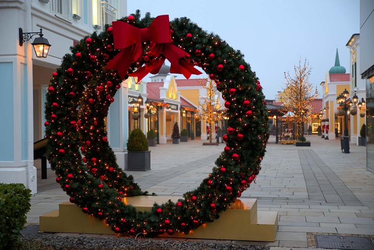 Zu den Sehenswürdigkeiten bei Eisenstadt gehört das Designer Outlet Parndorf. Auf dem Bild sieht man einen großen Weihnachtskranz auf der Straße zwischen den Boutiquen. 