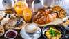 Essen in Wien: Frühstücken kann man in Wien an vielen, vielen Spots. Im Bild ein ausgiebiges Frühstück  auf verschiedenen Tellern mit Eierspeise, Cappuccino, Orangensaft, Croissants, Pancakes und Marmeladen.
