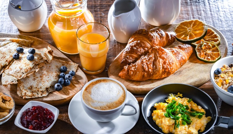 Essen in Wien: Frühstücken kann man in Wien an vielen, vielen Spots. Im Bild ein ausgiebiges Frühstück  auf verschiedenen Tellern mit Eierspeise, Cappuccino, Orangensaft, Croissants, Pancakes und Marmeladen.