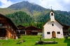 Zu Urlaub in Osttirol gehört ein Besuch von Innervillgraten. Auf dem Bild sieht man eine Kapelle und rustikale Häuser in den Bergen. 