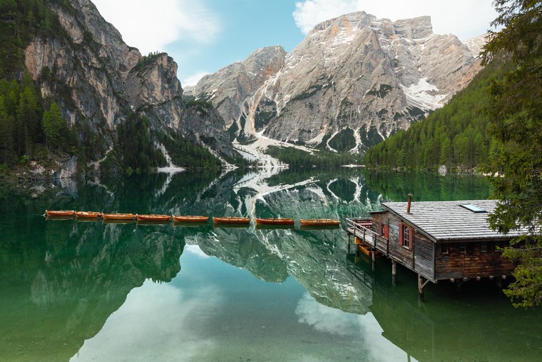 Pustertal: Blick auf den Pragser Wildsee an einem Spätsommertag. Der See ist blaugrün, dahinter schneebedeckte Gipfel. 