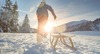 Eine Person zieht in einer schneebedeckten Landschaft einen Schlitten hinter sich her