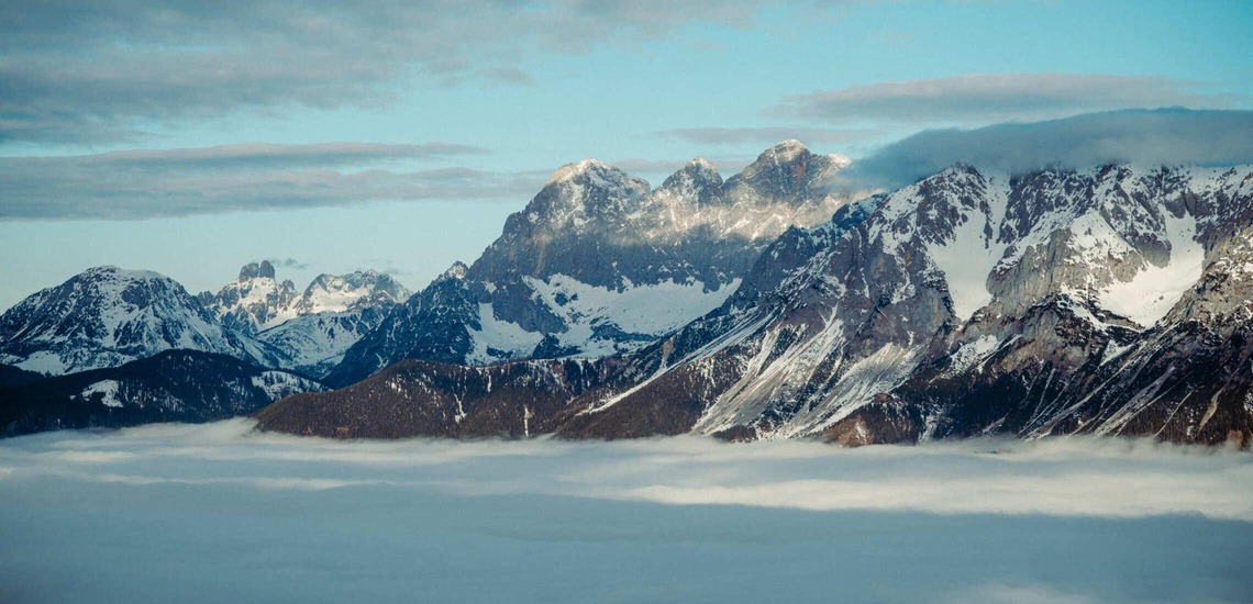 Schladming: Blick auf den schneebedeckten Dachstein, davor Wolken. 