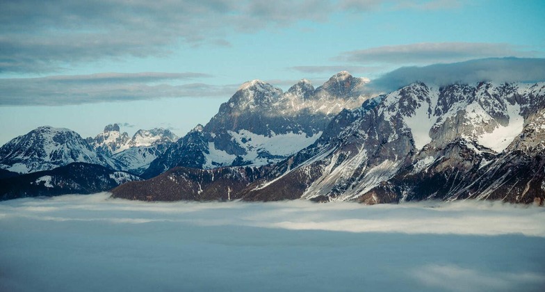 Schladming: Blick auf den schneebedeckten Dachstein, davor Wolken. 