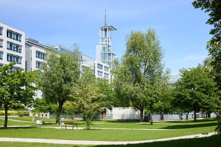 Zu den Sehenswürdigkeiten St. Pölten gehört der Klangturm. Auf dem Bild sieht man ihn im Regierungsviertel, davor Bäume und grüne Rasenflächen. 