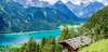 Tirol Ausflugsziele: Blick auf den Achensee in Tirol und die dahinterliegenden Berge. Im Vordergrund eine Almhütte. 