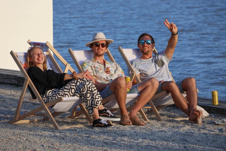 Beach and Surf Fest 2026: Die besten Festivals in Österreich 2026: Im Bild sieht man drei Personen, wie sie entspannt in Liegestühlen an einem Strand entspannen. 
