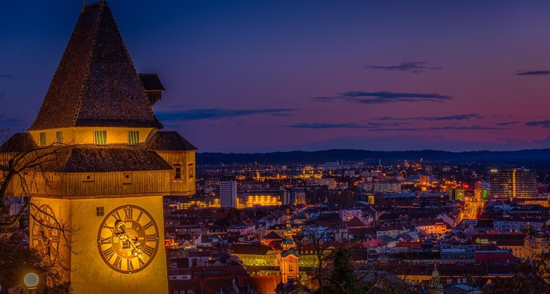 Graz Sehenswürdigkeiten: Der Uhrturm bei Nacht, mit Blick auf die Stadt