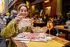 Zu den Bologna Sehenswürdigkeiten gehört auf jeden Fall die Kulinarik. Auf dem Bild sieht man eine Frau, die an einem Tisch im freien, vor einem Restaurant, Mortadella isst und dabei lächelt. 