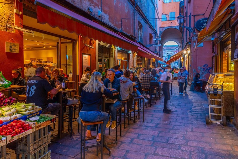 Zu den Bologna Sehenswürdigkeiten gehört das Nachtleben im Universitätsviertel. Auf dem Bild sieht man Leute in Straßen-Bars.