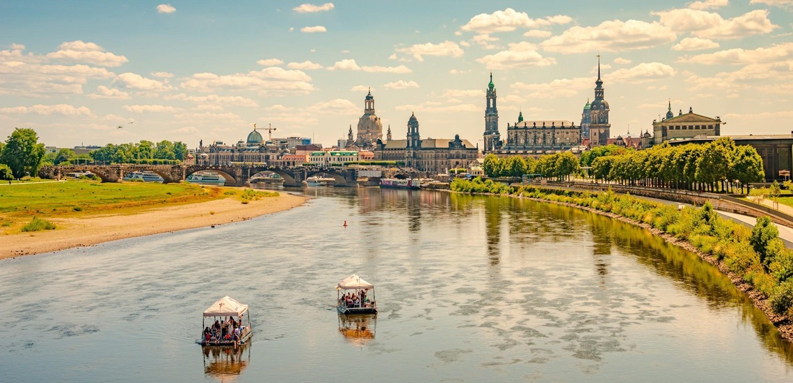 Dresden Sehenswürdigkeiten: Blick auf die Elbe und die Altstadt von Dresden an einem Sommertag. Die Ufer des Flusses sind grün. 