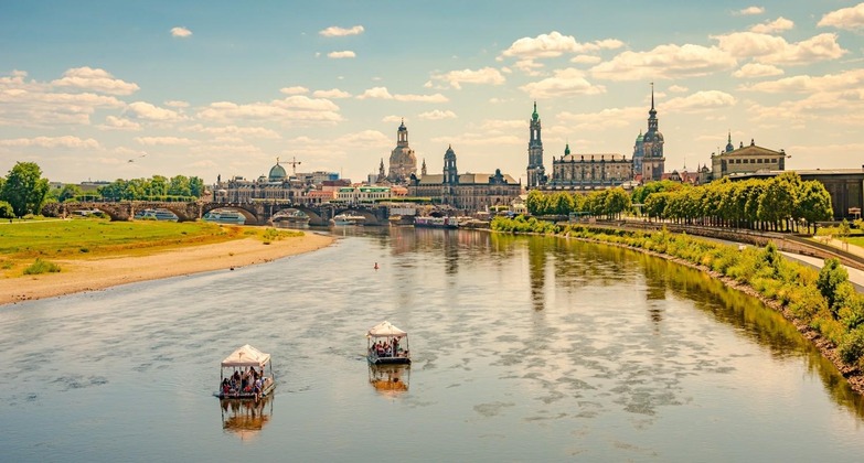 Dresden Sehenswürdigkeiten: Blick auf die Elbe und die Altstadt von Dresden an einem Sommertag. Die Ufer des Flusses sind grün bewachsen. 