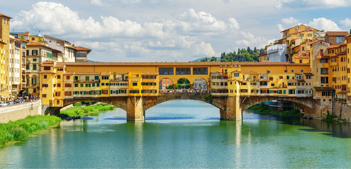Zu den top Sehenswürdigkeiten in Florenz gehört die Brücke Ponte Vecchio. Auf dem Bild sieht man sie an einem sonnigen Tag. 