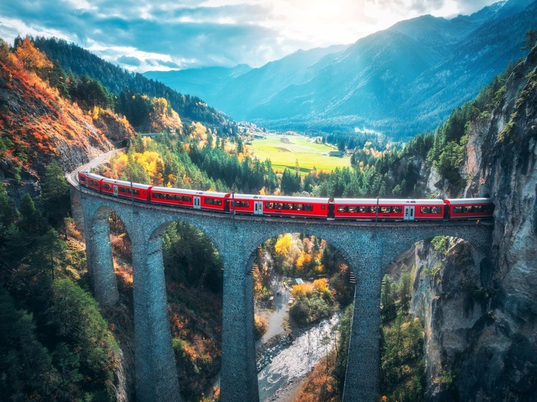 Auf der Glacier Express Route liegt das Landwasserviadukt. Auf dem Bild sieht man den Glacier Express auf dem Landwasserviadukt bei herbstlichem Wetter. 