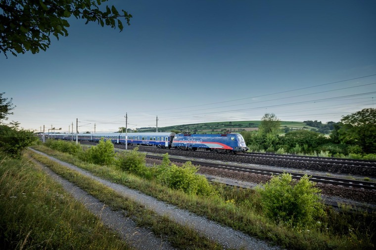 Günstig reisen: Ein Nightjet fährt bei sommerlicher Witterung auf den Gleisen. 