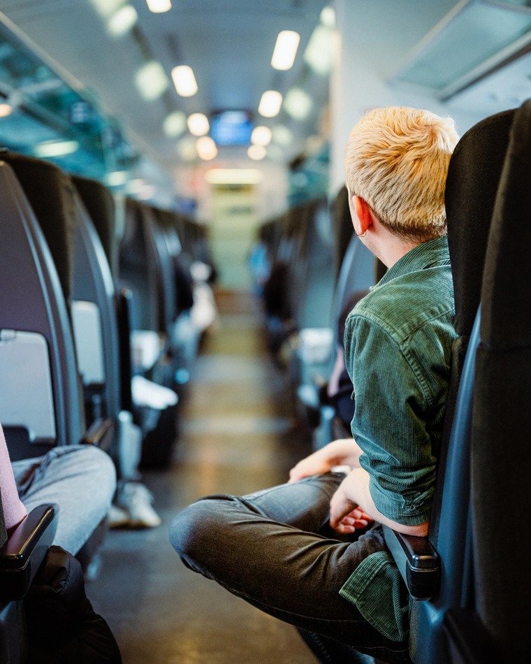 Günstig reisen: Ein junger Mann blickt im Gang eines Zugwaggons nach vorne. 