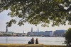 Hamburg Highlights: Zwei Menschen sitzen am Flussufer und Blicken auf die Stadt