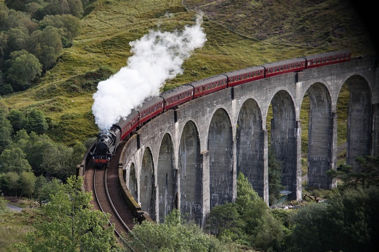 Interrail Routen: Die West Highland Line und der Glenfinnan-Viadukt, hier mit einer alten Dampflok zu sehen, ist eine der schönsten Eisenbahnstrecken der Welt.