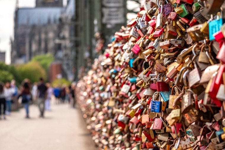 Zu den Sehenswürdigkeiten in Köln gehört die Hohenzollernbrücke. Auf dem Foto sieht man viele bunte Schlösser mit persönlichen Gravuren von Verliebten.