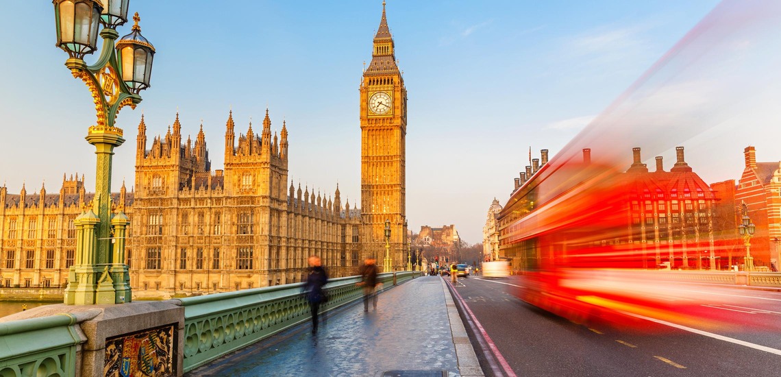 Sehenswürdigkeiten von London: Im Hintergrund der Big Ben, auf der Straße fährt ein roter Doppeldeckerbus vorbei. 